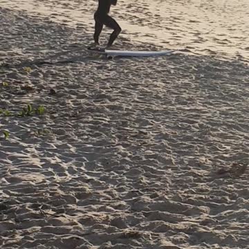 A man in black wet suit stretching on beach