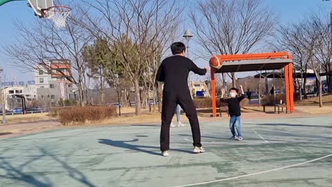 A father and a son playing basketball.