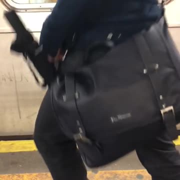Man with umbrella in bag gets excited about train coming