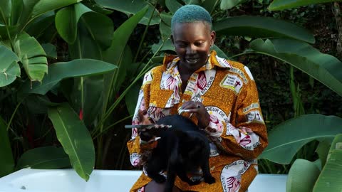 Black girl wearing colourful shirt playing with a black cat