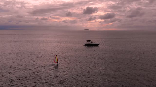 Windsurfer and a yacht in the ocean