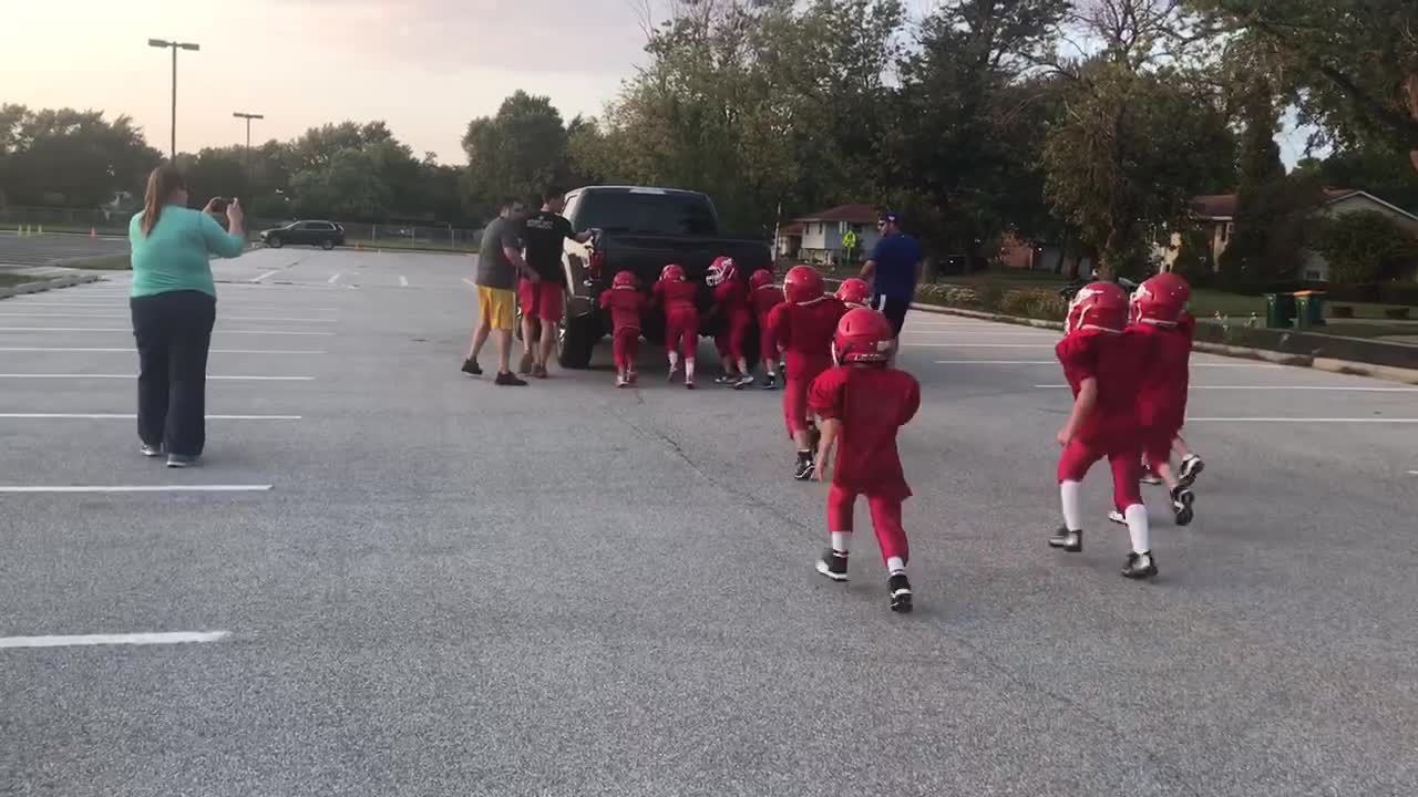 Youth Football Team Pushes Truck Around Parking Lot