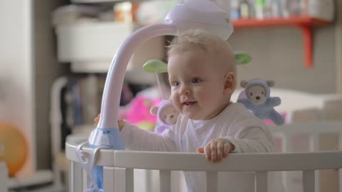 Baby girl holding onto her crib