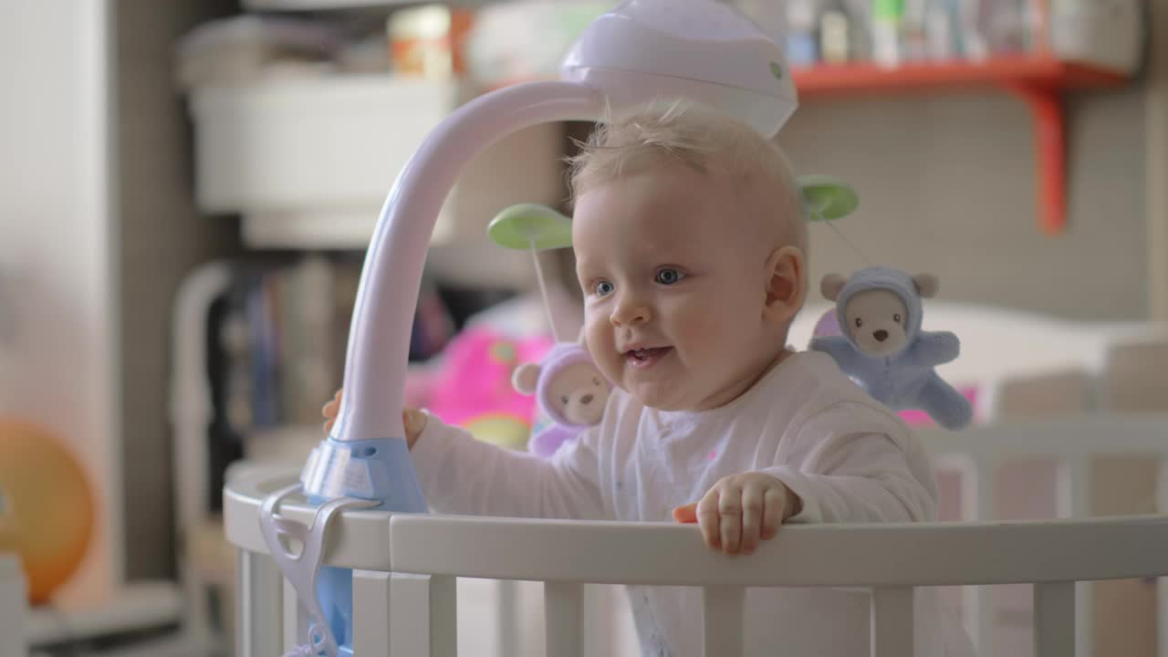 Baby girl holding onto her crib