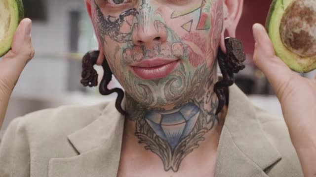 Young Tattooed Man Posing with Avocado Halves