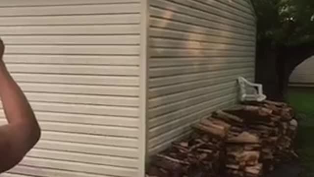 Shirtless man jumps from garage onto white table in back yard