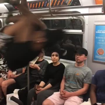 Two people dancing on poles and railing on subway swinging spinning