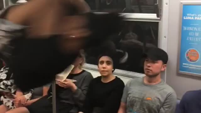 Two people dancing on poles and railing on subway swinging spinning