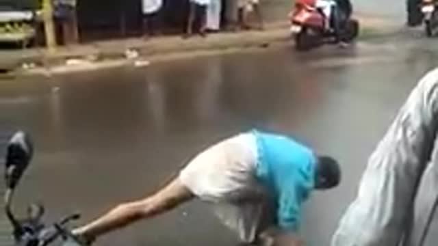 Guy in blue shirt practices kicking and stretching on a busy road
