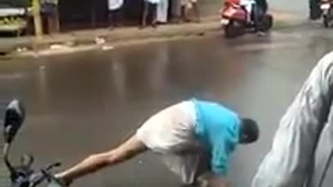 Guy in blue shirt practices kicking and stretching on a busy road