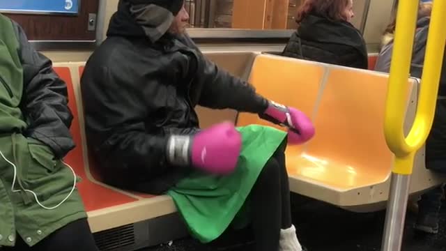 Man green skirt pink boxing gloves on train