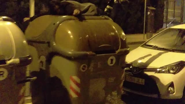 Guy in black shirt jumps from white car unto trash can