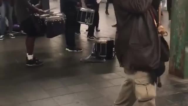 Old man with cane dances to drummers in subway