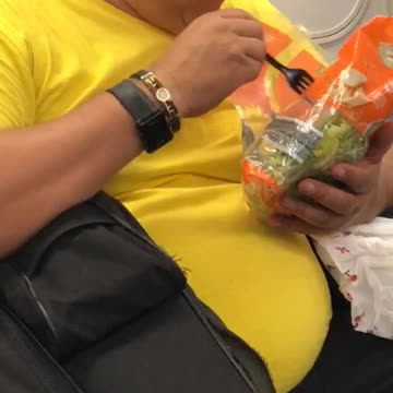 Guy yellow shirt eating salad out of bag