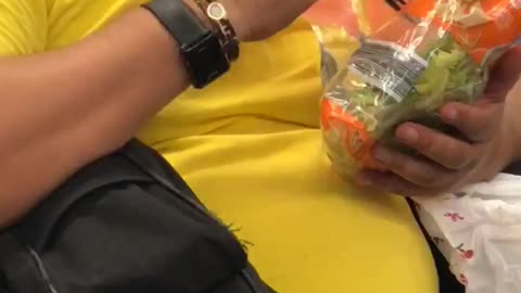 Guy yellow shirt eating salad out of bag