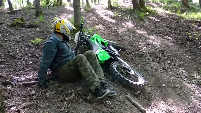 Green dirtbike tries to go up dirt hill guy falls over