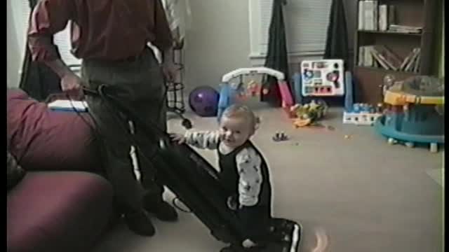 Baby Boy Rides Vacuum Cleaner While Dad Cleans