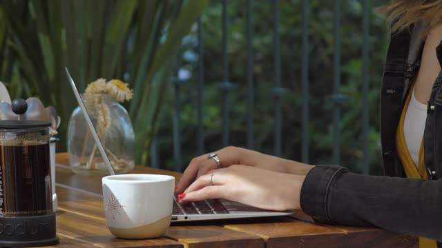 Woman typing on her laptop in a coffee shop