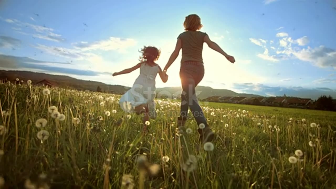 Mother and her little daughter running in the meadow at sunset.