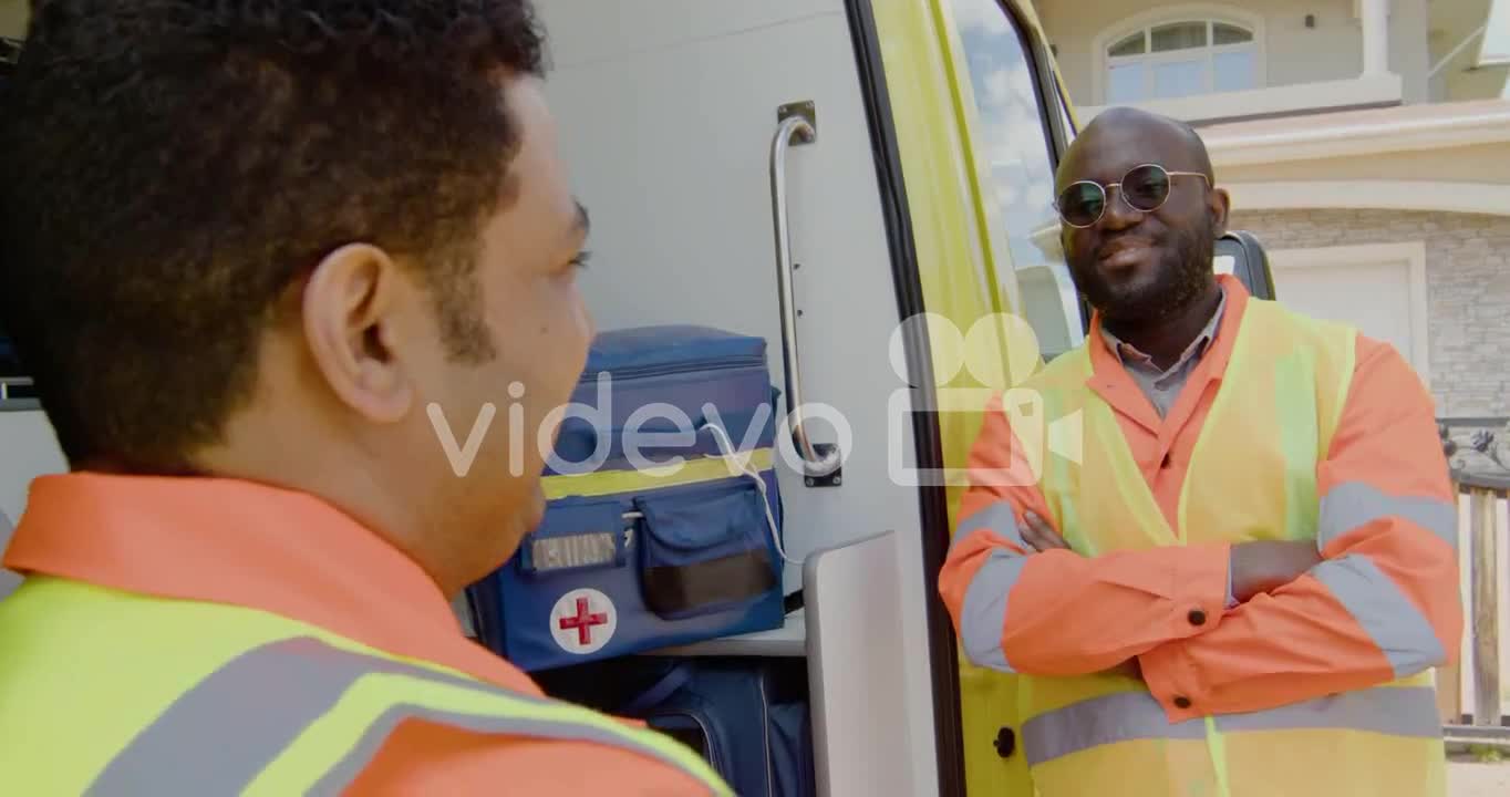 Two Medical Assistants Talking In Front Of An Ambulance 1