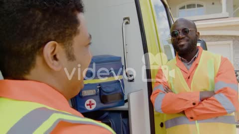 Two Medical Assistants Talking In Front Of An Ambulance 1