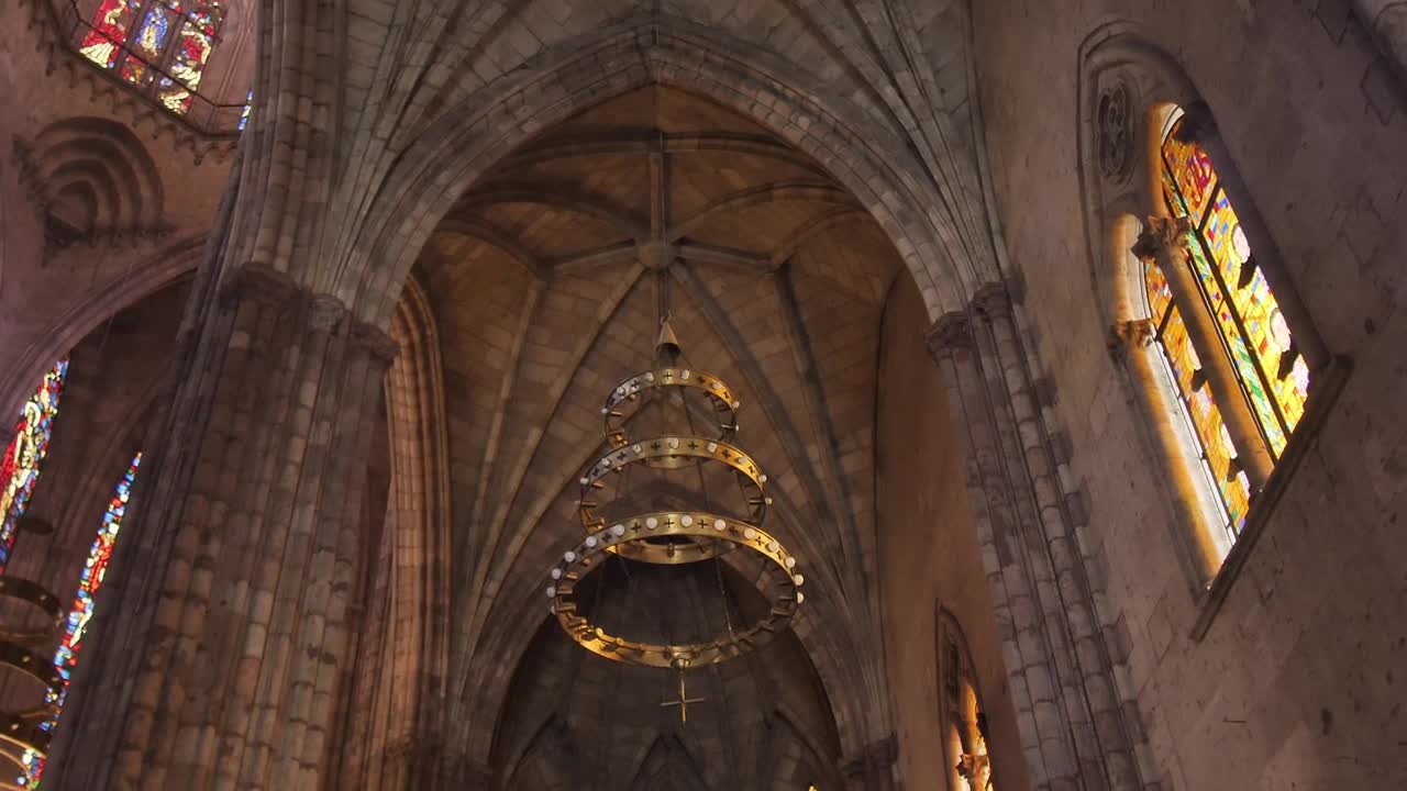 Gothic church inside with colorful stained glass windows and a large chandelier