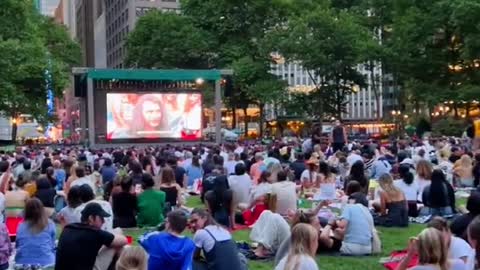 An open-air movie in a park is crowded with people.