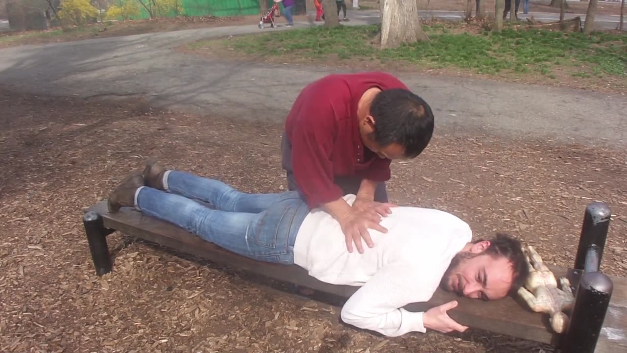 Luodong Briefly Massages White Man In White Shirt On Park Bench