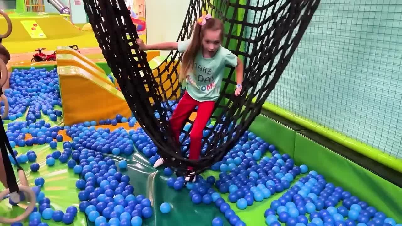 Sofia and a lot of colored balls on the Playground for kids