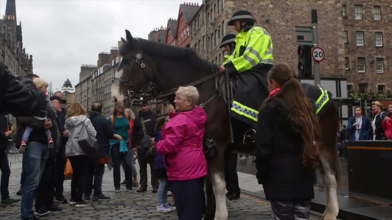 Two horse mounted police officers stand watch over tourists on the Royal Mile during the Festival