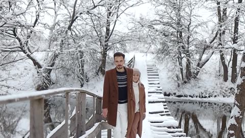 Watch a Couple Stroll Across a Snow Covered Bridge in a Breathtaking Scene