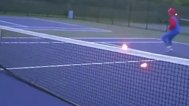 Two boys were playing a burning tennis ball on a tennis court