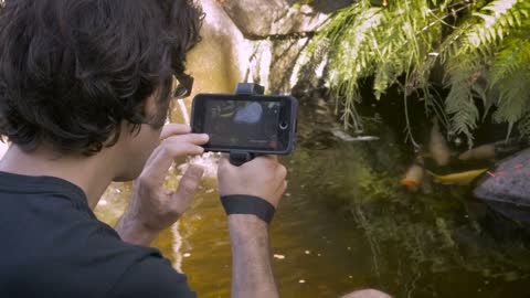 A middle aged dark haired man shoots video with his mobile phone