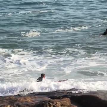 Man in black wet suit with red surf board