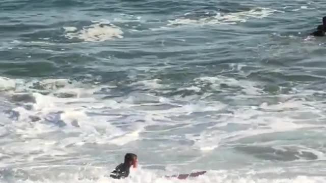 Man in black wet suit with red surf board