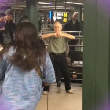 Zoom in on old man green shirt dancing in subway