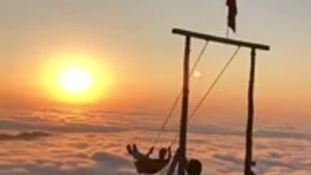 A man swinging over clouds