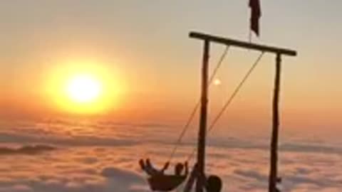 A man swinging over clouds