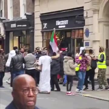 Men holding the Sudanese flag attempt to storm a Hackett store in London