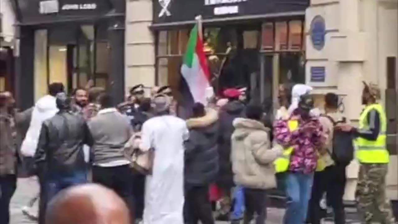 Men holding the Sudanese flag attempt to storm a Hackett store in London