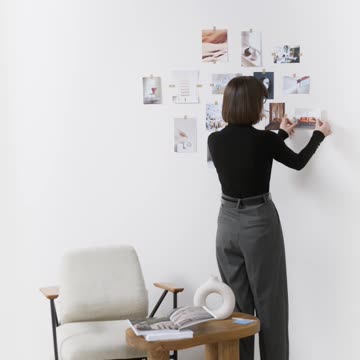 A Woman Pasting Pictures on the Wall