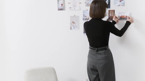 A Woman Pasting Pictures on the Wall