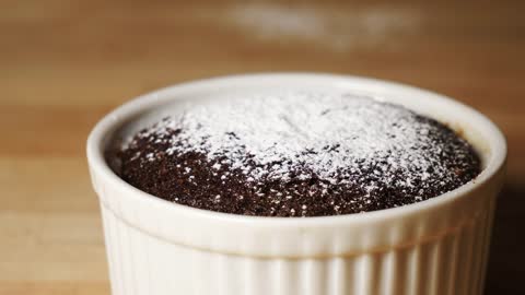 Powdered sugar being sprinkled on a chocolate cake