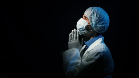 Doctor praying in a dark room looking at sky