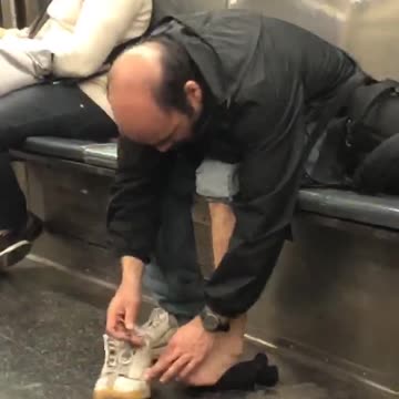 Bald man takes shoe off on subway