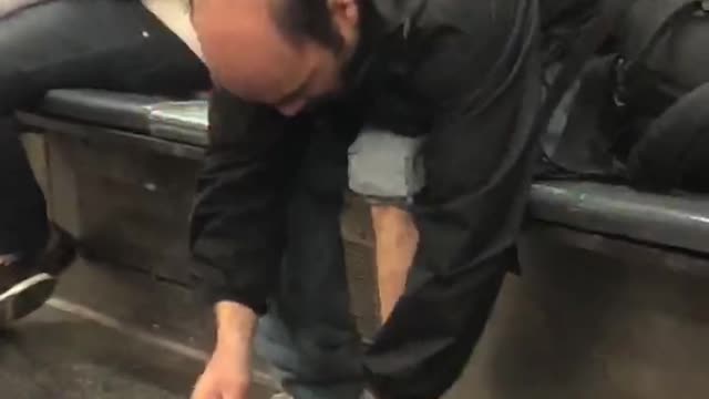 Bald man takes shoe off on subway