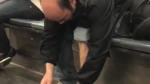 Bald man takes shoe off on subway