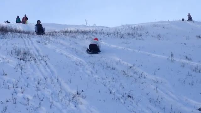 Kid white jacket orange beanie roll down snowy hill