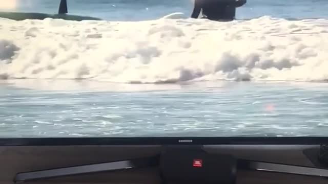 Guy records tv of man wiping out on surfboard