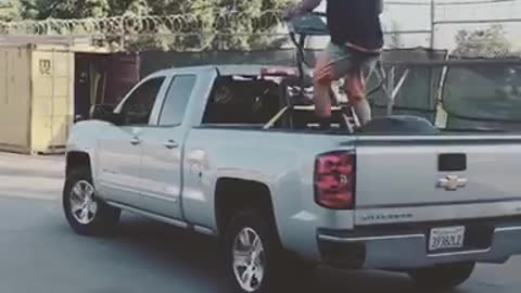 A man on a treadmill on the back of a silver truck